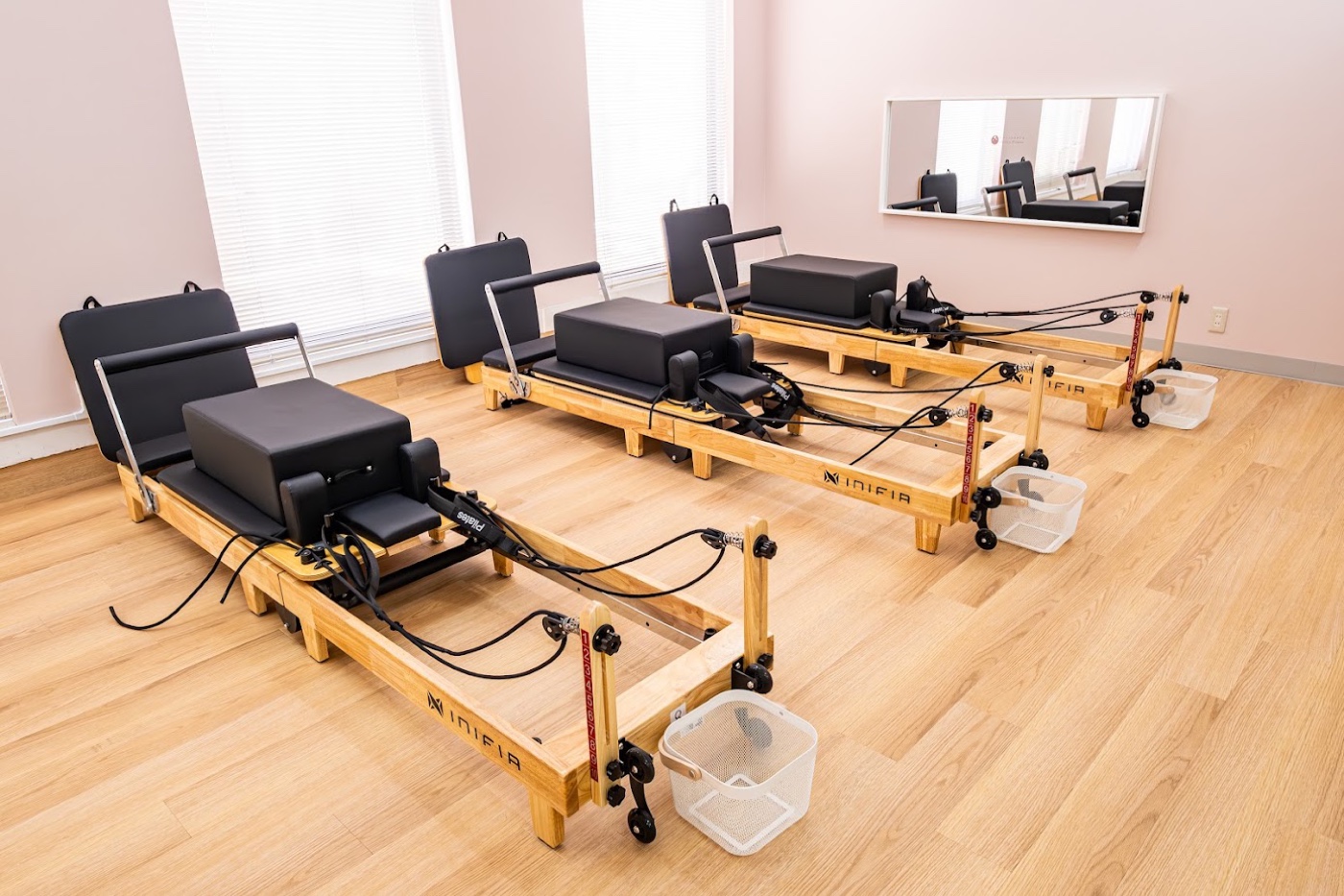 cocoro Pilates 沼津駅前店に設置されたINIFIA製リフォーマー3台。木製フレーム・黒いレザーのキャリッジ・スプリング・フットバーが見える俯瞰。